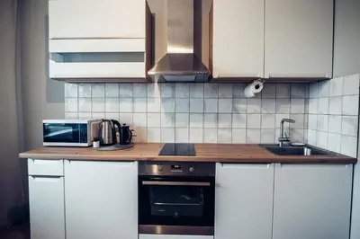 a kitchen with white cabinets and a sink and a microwave at Pine Apartment in Visaginas