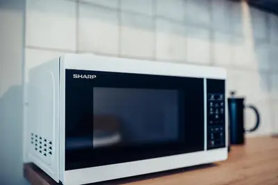 a white microwave oven sitting on a wooden table at Pine Apartment in Visaginas