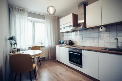 a kitchen with white cabinets and a table and a window at Pine Apartment in Visaginas