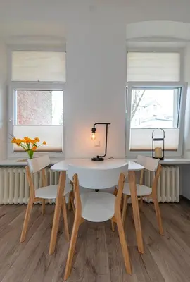 a dining room with a table and chairs and two windows at Freedom Avenue Apartment by Polo apartments in Kaunas