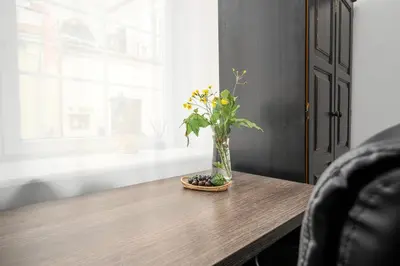 a vase of flowers on a wooden table with a window at Capital's Old Town Gem in Vilnius