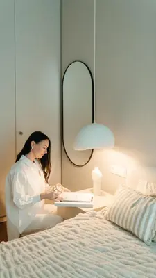 a woman sitting at a desk next to a bed at Home in in Druskininkai