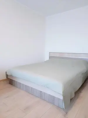 a bed in a room with a white wall at Adomo Apartamentai Panevėžyje in Panevėžys