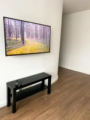 a tv hanging on a wall in a room with a table at 