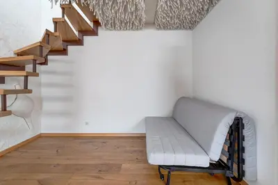 a room with a staircase with a bench and wooden floors at Charming Loft in Vilnius Oldtown in Vilnius