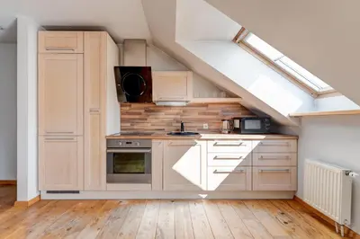 an attic kitchen with white cabinets and a stove at Charming Loft in Vilnius Oldtown in Vilnius