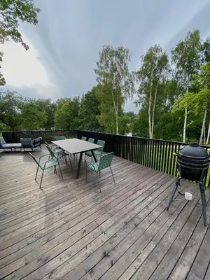 a grill on a wooden deck with a picnic table and chairs at Island House atostogų namai in Gaylyunay