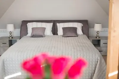 a bedroom with a white bed with pink flowers at Petro studija in Kaunas