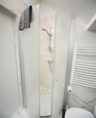 a white bathroom with a shower and a toilet at Petro studija in Kaunas