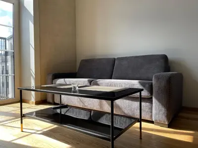 a living room with a couch and a glass table at Center stay Kaunas - Peledyne - Owl's nest apartments in Kaunas