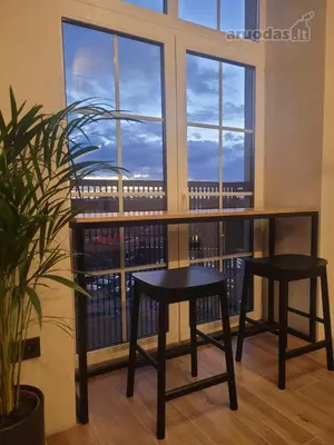 a table and two stools in front of a window at Center stay Kaunas - Peledyne - Owl's nest apartments in Kaunas