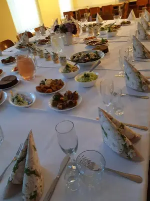 a long table with plates of food and wine glasses at Kriaunų bendruomenės Svečių namai in Gipenai