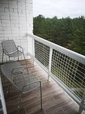 two chairs on a balcony with a view of trees at Studio Apartment with Lake View in Visaginas