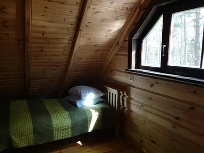 a small room with a bed in a log cabin at Antalieptės sodyba in Baibiai