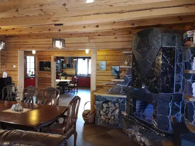 a dining room with a stone fireplace in a log cabin at Antalieptės sodyba in Baibiai