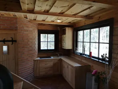 a kitchen with wooden cabinets and a brick wall at Antalieptės sodyba in Baibiai