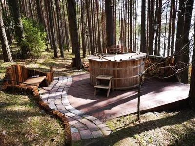 a wooden deck with a hot tub in the woods at Antalieptės sodyba in Baibiai