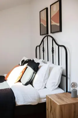 a bed with white pillows and a wooden table at #stayhere - Modern & Central 2 Bedroom Apartment in Vilnius
