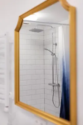 a bathroom mirror with a shower with a blue shower curtain at #stayhere - Modern & Central 2 Bedroom Apartment in Vilnius
