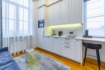 a kitchen with white cabinets and a blue couch at Ministerija Loft Apartment with parking & AC in Kaunas