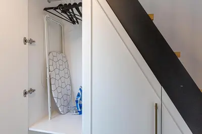 a room with a staircase with a white cabinet next to a stair case at Ministerija Loft Apartment with parking & AC in Kaunas