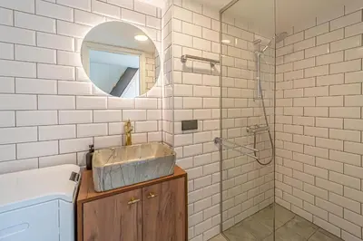 a bathroom with a sink and a shower with a mirror at Ministerija Loft Apartment with parking & AC in Kaunas