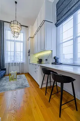 a kitchen with white cabinets and a table and chairs at Ministerija Loft Apartment with parking & AC in Kaunas