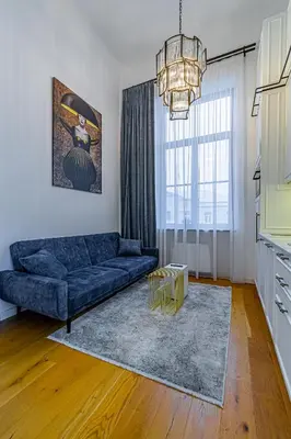 a living room with a blue couch and a chandelier at Ministerija Loft Apartment with parking & AC in Kaunas