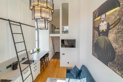 a room with a staircase and a living room with a kitchen at Ministerija Loft Apartment with parking & AC in Kaunas