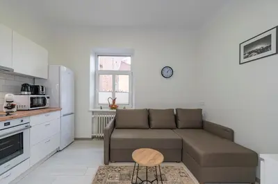 a living room with a couch and a kitchen at Historical Oldtown Charm with Modern Comfort by Polo Apartments in Kaunas