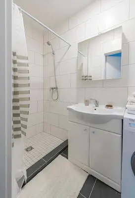 a white bathroom with a shower and a sink at Historical Oldtown Charm with Modern Comfort by Polo Apartments in Kaunas