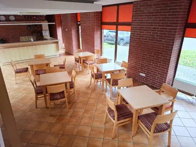 an empty restaurant with wooden tables and chairs at LUNA Marijampole in Marijampolė