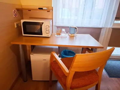a small table with a microwave and a chair at LUNA Marijampole in Marijampolė