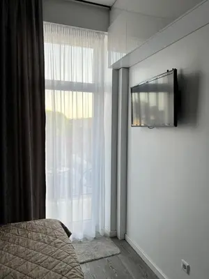 a bedroom with a window with a television on a wall at Arena apartment in Kaunas
