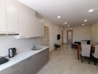 a kitchen with white cabinets and a dining room at Antonio house in Ramučiai