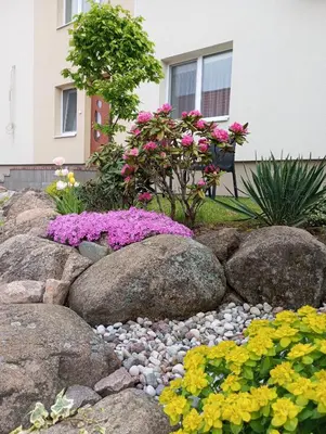 a garden with rocks and flowers in front of a house at Antonio house in Ramučiai