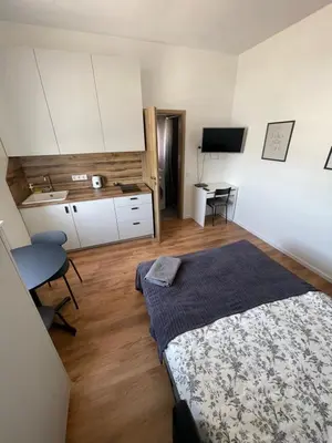 a bedroom with a bed and a kitchen with a desk at 29 Airport Apartment in Vilnius