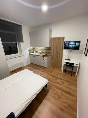 a bedroom with a bed and a desk and a kitchen at 29 Airport Apartment in Vilnius