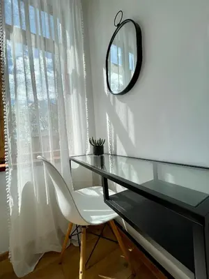 a glass desk with a white chair and a mirror at Kaunas Green in Kaunas