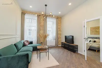 a living room with a green couch and a television at FREE PARKING Old Town Central Station Apart with Balcony in Vilnius