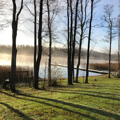 a view of a lake with trees in the foreground at Sodyba Paukščių Takas in Aviliai