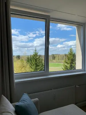 two windows in a room with a view of a golf course at VANDUO Anykščiuose in Anykščiai