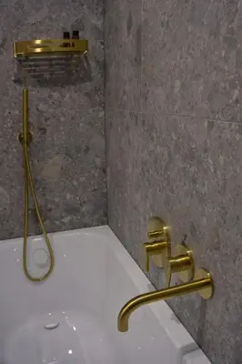 a bathroom with a bath tub with a gold faucet at VANDUO Anykščiuose in Anykščiai