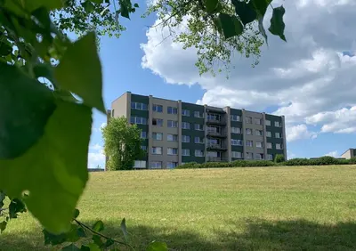 a building with a field in front of a building at VANDUO Anykščiuose in Anykščiai