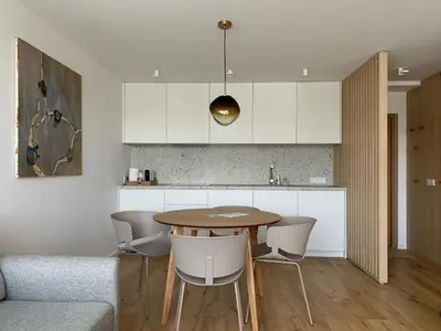 a kitchen with a wooden table and white cabinets at SMĖLIS Anykščiuose in Anykščiai