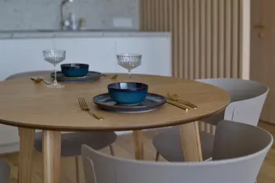 a wooden table with two blue plates and wine glasses at SMĖLIS Anykščiuose in Anykščiai